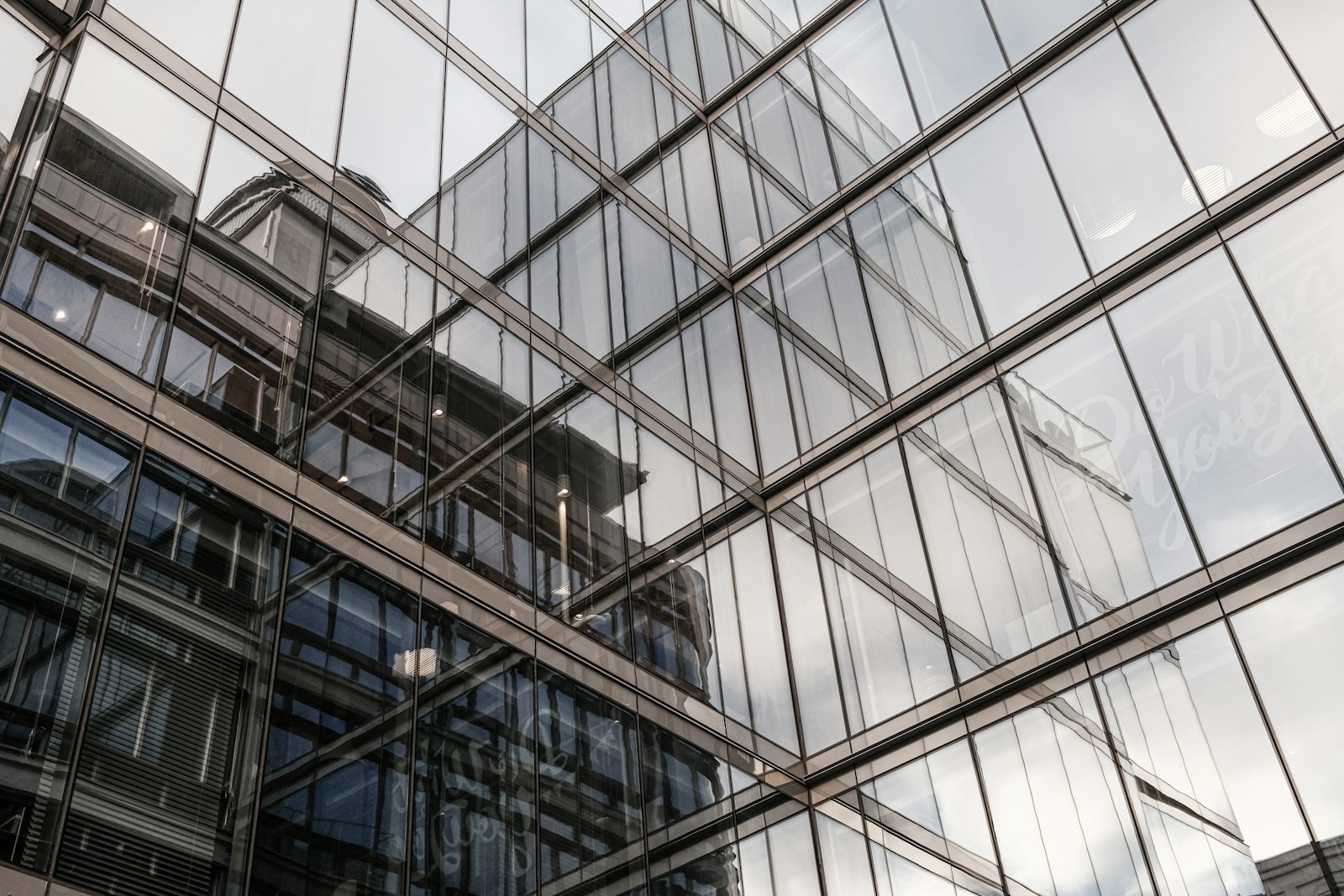 Glass office facade reflecting neighbouring buildings, representing professional services firms