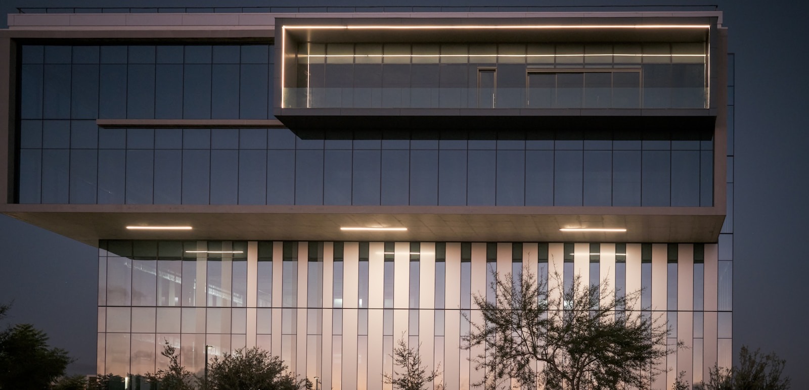 Illuminated modern office building at dusk representing trading and brokerage firms